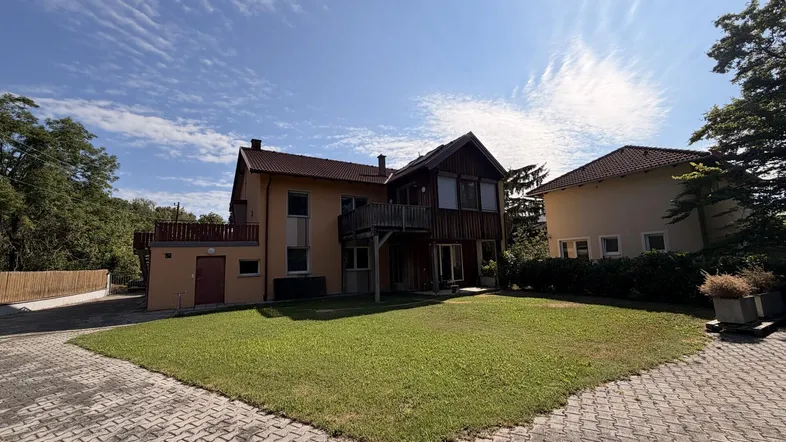 Vorderansicht des Hauses mit gepflegtem Rasen und gepflasterter Auffahrt unter blauem Himmel.