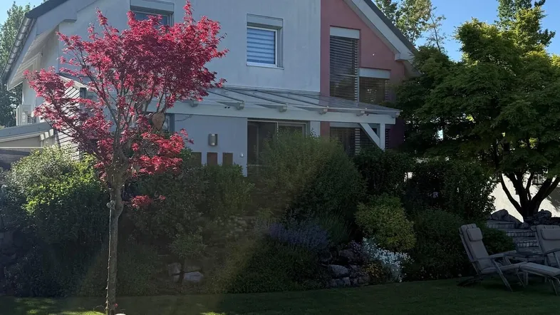 Großzügiger Gartenbereich mit gepflegtem Rasen, blühenden Pflanzen und einem Pool mit Abdeckung.