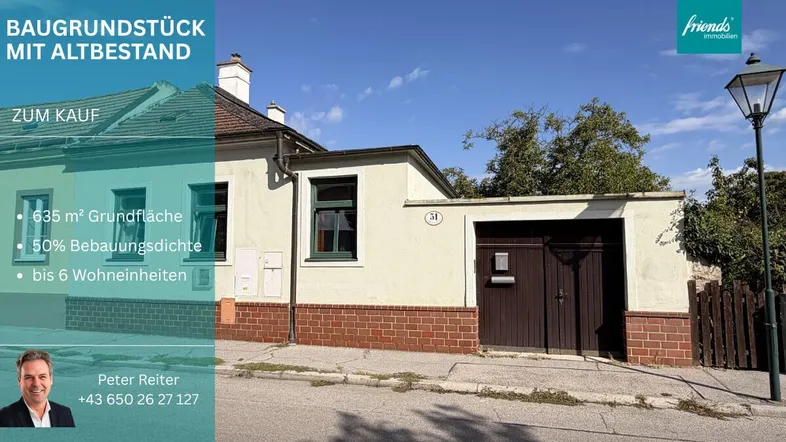 Vorderansicht eines älteren Hauses mit Garage und Werbebanner für ein Baugrundstück.