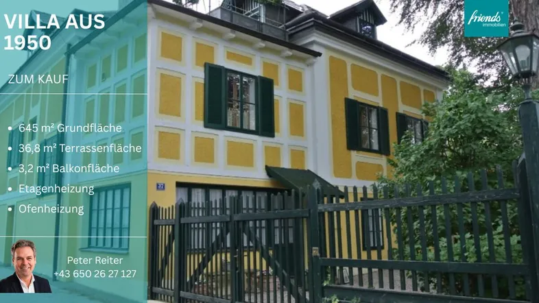 Historische Villa aus dem Jahr 1950 mit gelber Fassade und grünen Fensterläden, umgeben von einem Zaun.