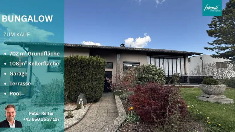 Außenansicht des Bungalows mit gepflegtem Vorgarten, blühenden Sträuchern und einem klaren blauen Himmel.