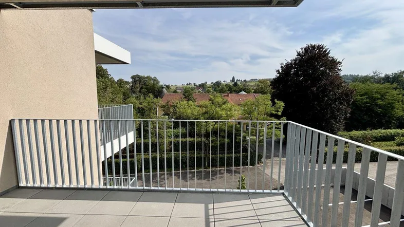 Geräumiger Balkon mit Fliesenboden und weitem Blick ins Grüne und auf die umliegende Landschaft.