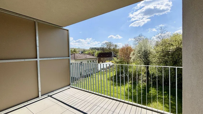 Heller Balkon mit Fliesenboden und weitem Blick ins Grüne und auf die Umgebung.