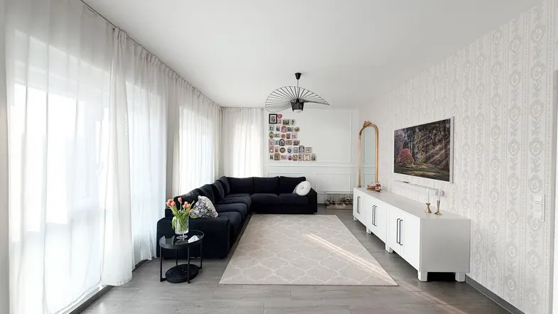 Helles Wohnzimmer mit großem Ecksofa, modernem TV-Möbel und gemusterten Tapeten.