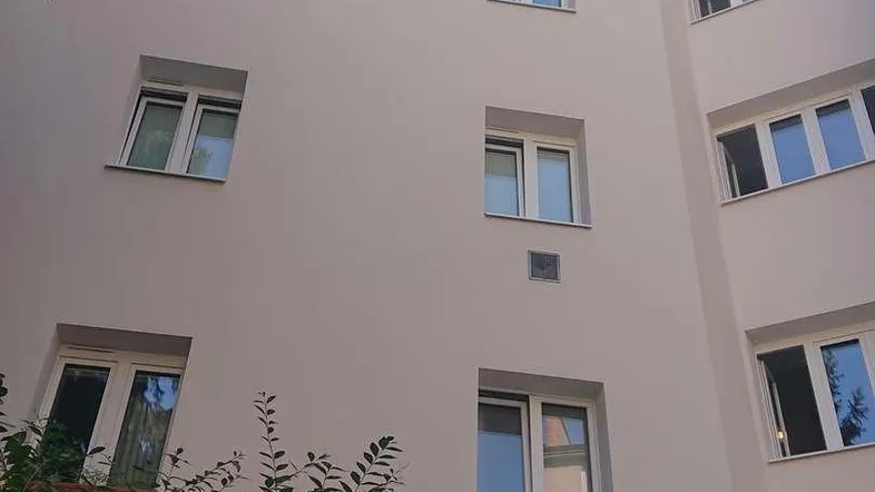 Ansicht der modernen Gebäudefassade mit zahlreichen Fenstern und umgebendem Grün.