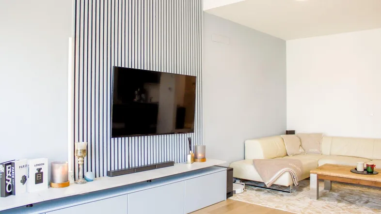 Modernes Wohnzimmer mit hellem Sofa, Holzboden und vertikalen Wandpaneelen.