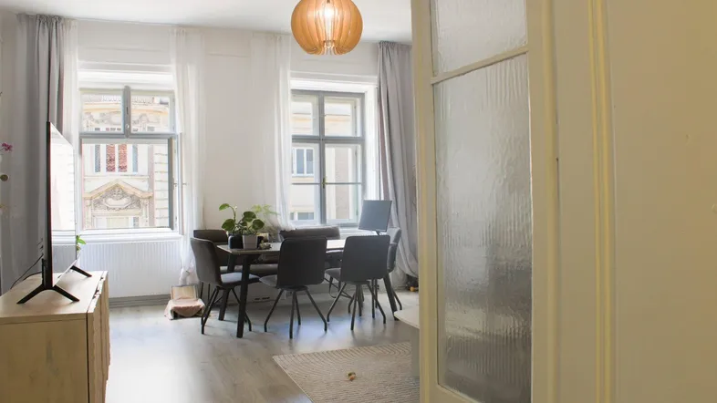 Helles Wohn- und Esszimmer mit Holzboden, modernem Esstisch und Blick auf die Stadt.