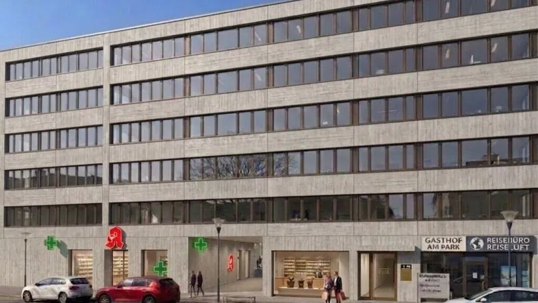 Modernes Geschäftsgebäude mit vielen Fenstern und verschiedenen Ladenlokalen im Erdgeschoss, darunter eine Apotheke und ein Gasthof.