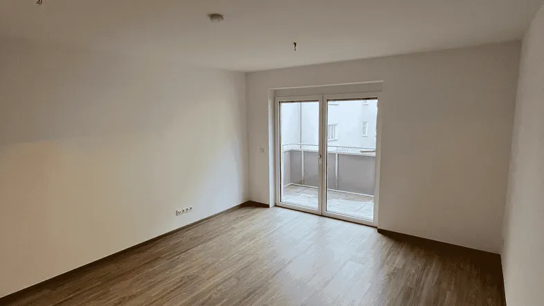 Helles Zimmer mit Laminatboden und Zugang zu einem Balkon, ideal als Wohnbereich.