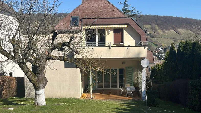Rückansicht des Hauses mit sonniger Terrasse, großem Garten und Blick auf die Weinberge.