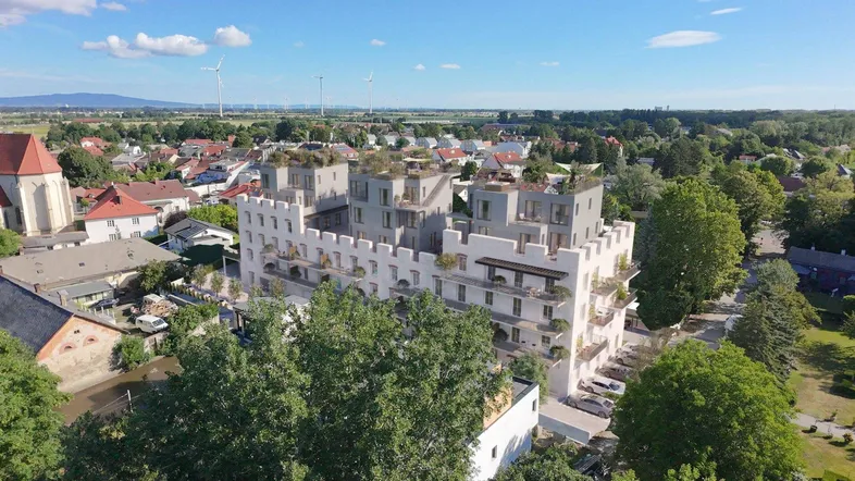 Luftaufnahme eines modernen Wohnkomplexes mit zinnenförmiger Fassade und umliegender Landschaft.