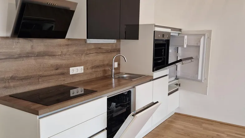 Moderne Einbauküche mit weißen Fronten, Holzoptik-Arbeitsplatte und integrierten Geräten.