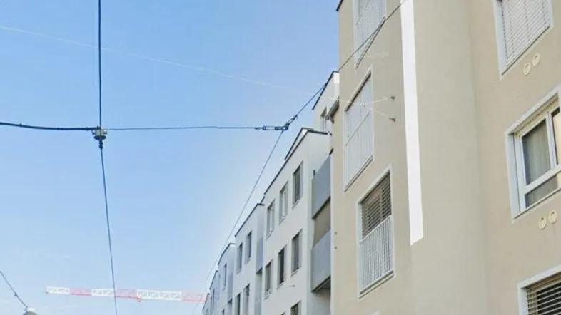 Moderne Wohngebäude entlang einer städtischen Straße unter blauem Himmel mit parkenden Autos.