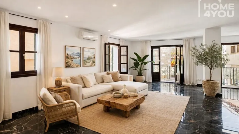 Helles Wohnzimmer mit beigem Ecksofa, Holztisch und Zugang zu einem französischen Balkon.