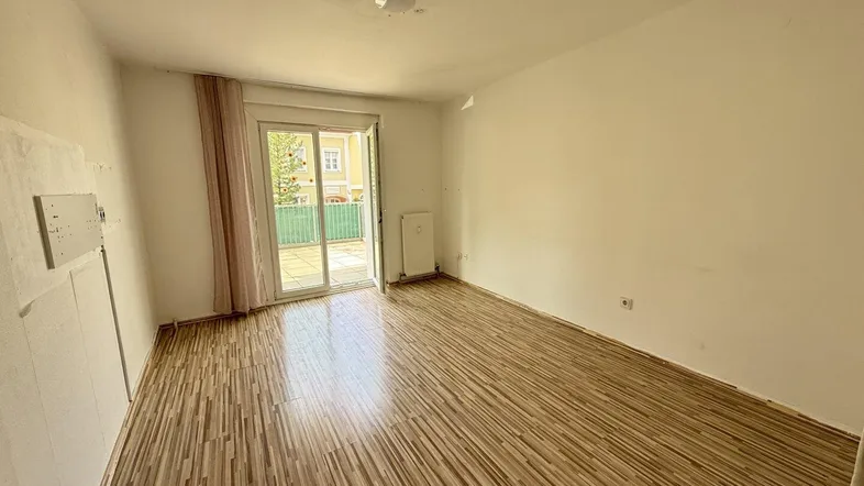Helles Zimmer mit Laminatboden und direktem Zugang zu einer Außenterrasse.