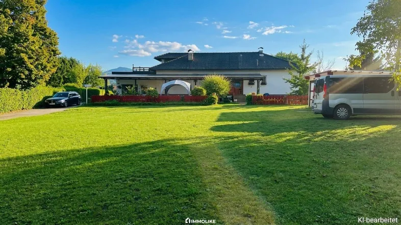 Großzügiger Gartenbereich mit Rasenfläche und Blick auf das Wohnhaus unter blauem Himmel.
