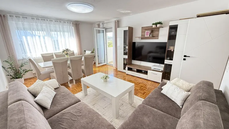 Geräumiger Wohn-Essbereich mit bequemer Sitzecke, Esstisch und Zugang zum Balkon.