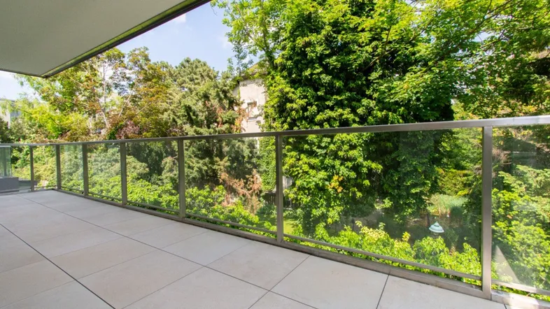 Großer Balkon mit moderner Glasbrüstung und weitem Blick ins Grüne, perfekt für sonnige Tage.