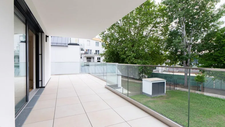 Große, moderne Terrasse mit Fliesenboden, Glasgeländer und Blick ins Grüne sowie auf die Stadt.
