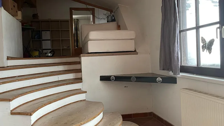 Gemütlicher Wohnbereich mit einzigartiger Holztreppe, Dachschrägen und Blick nach draußen.