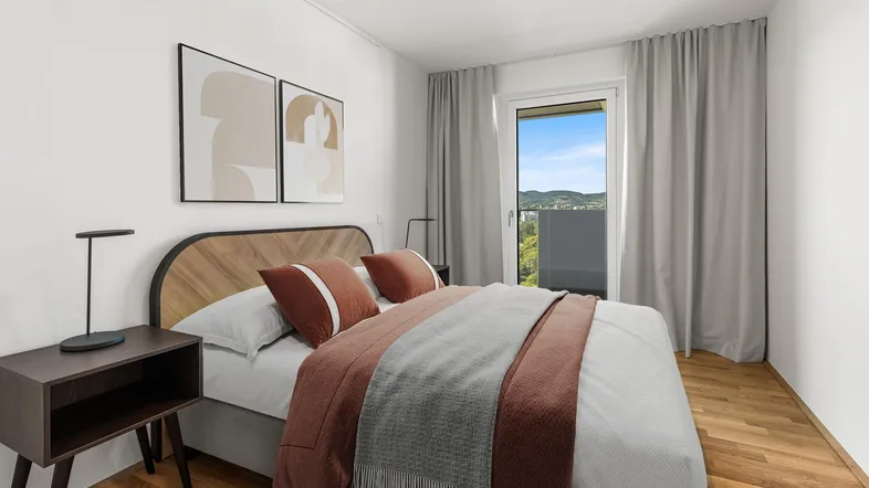 Helles Schlafzimmer mit Holzboden, modernem Bett und Zugang zum Balkon mit grüner Aussicht.