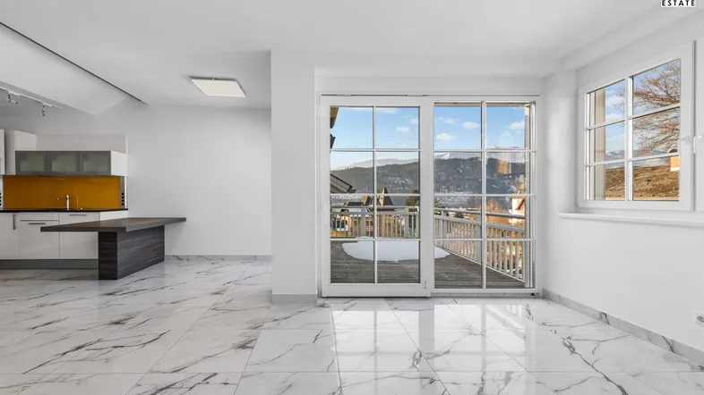 Heller offener Wohnbereich mit modernen Marmorfliesen und Zugang zu einem Balkon mit Bergblick.