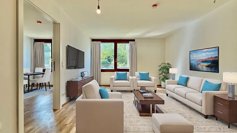 Modern eingerichtetes Wohnzimmer mit Holzboden, großen Fenstern und viel Tageslicht.