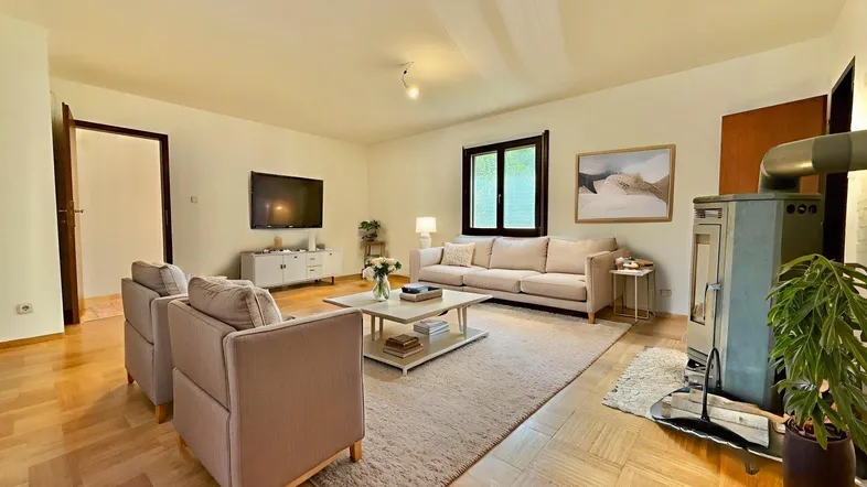 Gemütliches Wohnzimmer mit Kaminofen, bequemen Sofas und hellem Parkettboden.