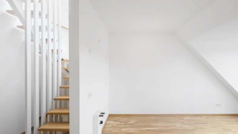 Heller Innenraum mit Holztreppe und Dachschräge, bereit für die individuelle Gestaltung.