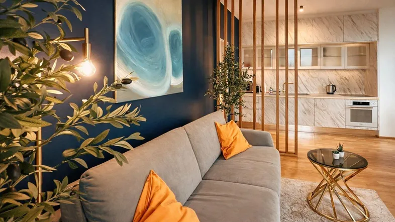 Moderner Wohnbereich mit dunkelblauer Wand, bequemer Couch und Blick auf die offene Küche.