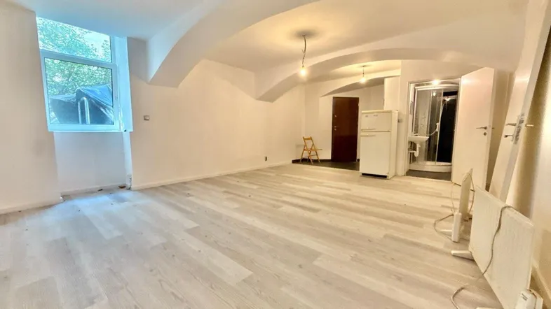 Geräumiger Wohnbereich mit hellem Laminatboden und gewölbter Decke, bietet viel natürliches Licht.