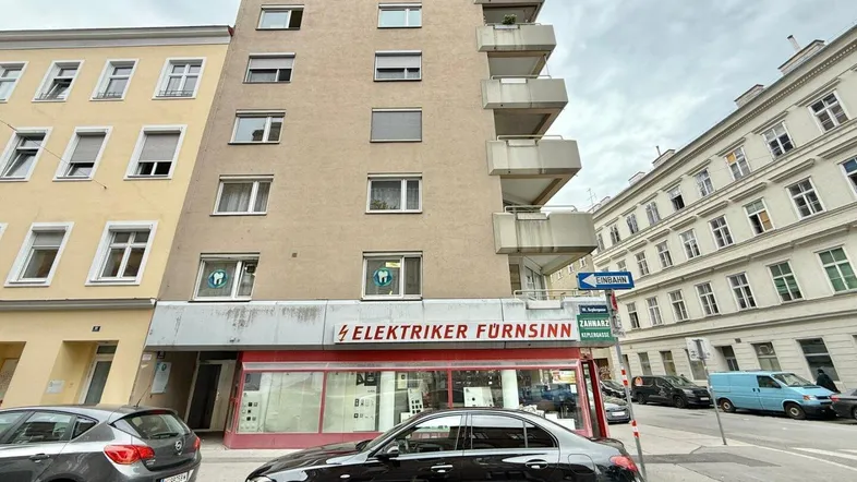 Mehrstöckiges Wohngebäude mit Balkonen an einer städtischen Straße.