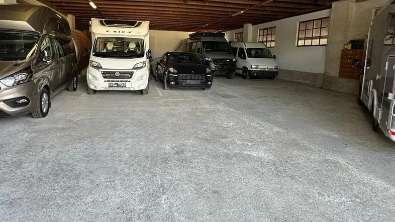 Geräumige und gut beleuchtete Garage mit Betonboden, ideal für Fahrzeuge und Wohnmobile.