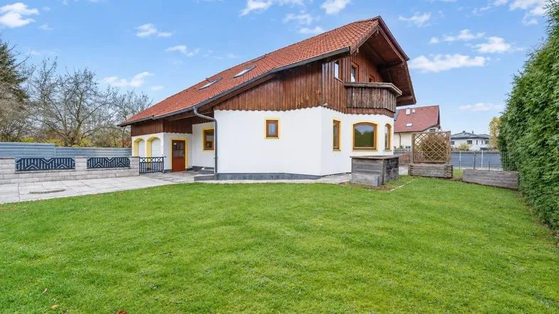 Ansicht des Hauses von der Seite mit gepflegtem Rasen und gepflastertem Bereich vor dem Eingang.