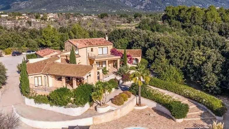Eine beeindruckende Villa mit großem Pool und weitläufigem Grundstück, umgeben von Bergen und üppiger Vegetation.