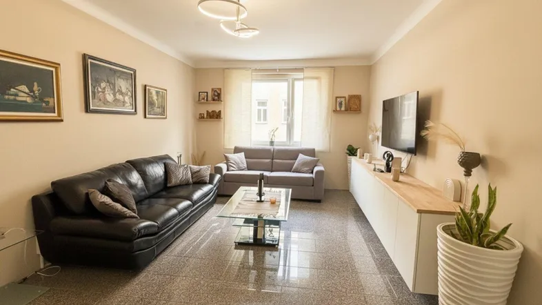 Helles Wohnzimmer mit Fliesenboden, bequemen Sofas und einem modernen Deckenlicht.