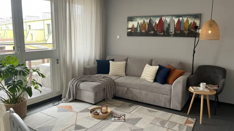 Gemütliches Wohnzimmer mit bequemer Couch, Teppich und Zugang zu einem Außenbereich.