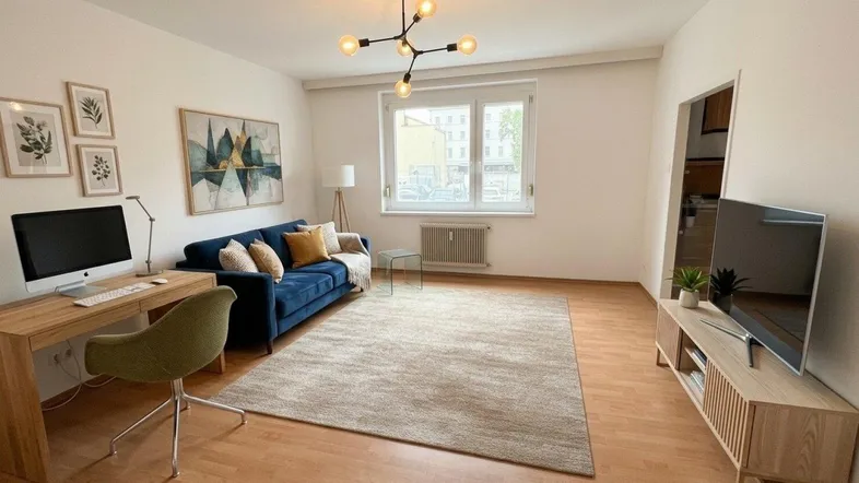 Helles Wohnzimmer mit modernem Sofa, Schreibtisch und Blick auf die Straße.