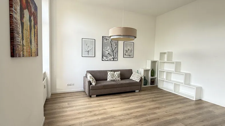 Helles Wohnzimmer mit modernem Laminatboden, einem Sofa und dekorativen Regalen.