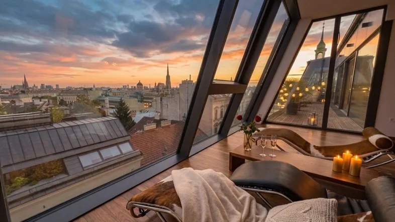 Gemütliches Wohnzimmer mit atemberaubendem Stadtblick bei Sonnenuntergang und großen Glasflächen.