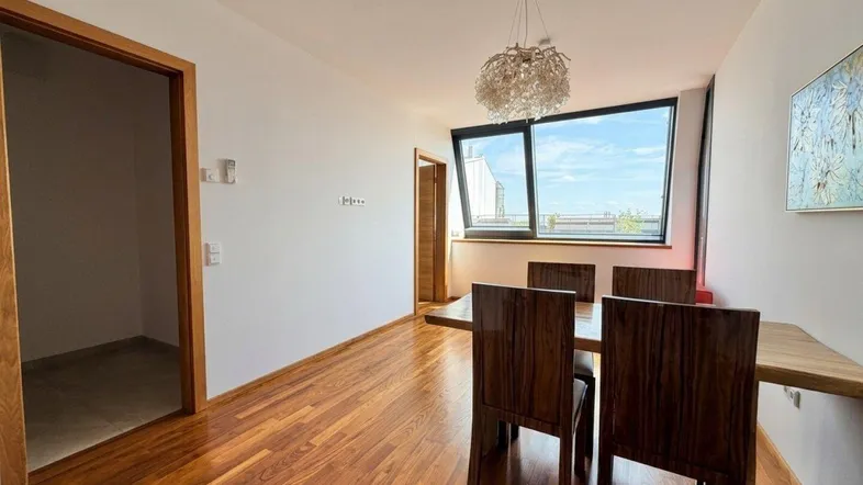 Heller Essbereich mit Holzboden, modernen Möbeln und großen Fenstern mit Ausblick.