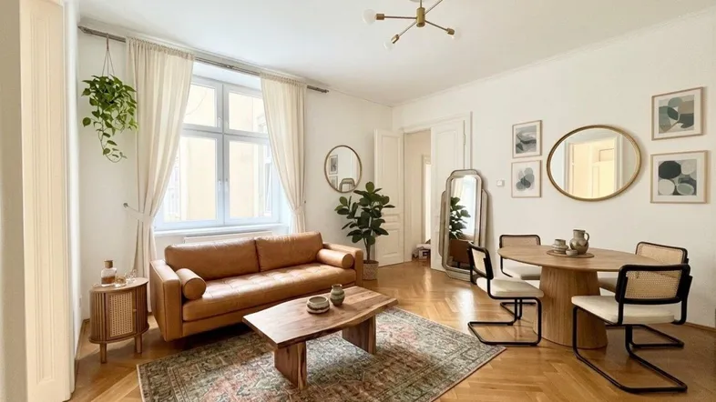 Heller Wohn- und Essbereich mit Fischgrätparkett, Ledersofa und modernem Esstisch.