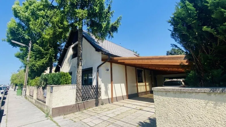 Einfamilienhaus mit Carport und Vorgarten, von der Straße aus gesehen.