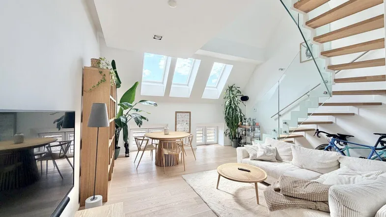 Helles, offenes Wohn-Esszimmer mit Holzboden, moderner Treppe und Dachfenstern für viel Tageslicht.