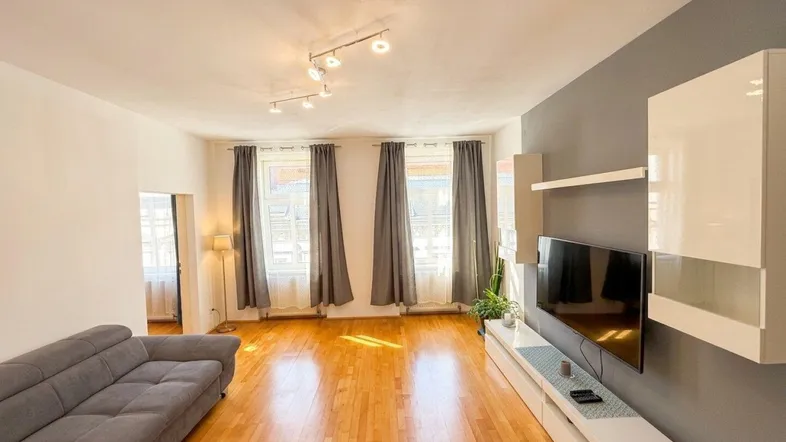 Helles Wohnzimmer mit Holzboden, grauer Akzentwand und modernen Möbeln.