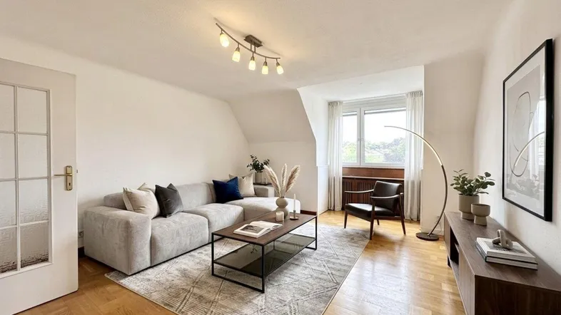 Helles Wohnzimmer mit gemütlichem Sofa, Parkettboden und Dachschrägen, modern eingerichtet.