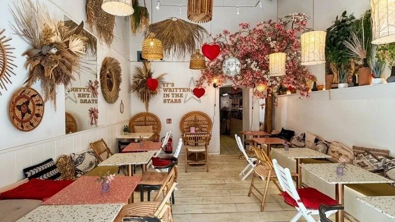 Gemütlicher Restaurantbereich mit floraler Dekoration, Rattanlampen und hellen Möbeln, ideal für entspannte Stunden.