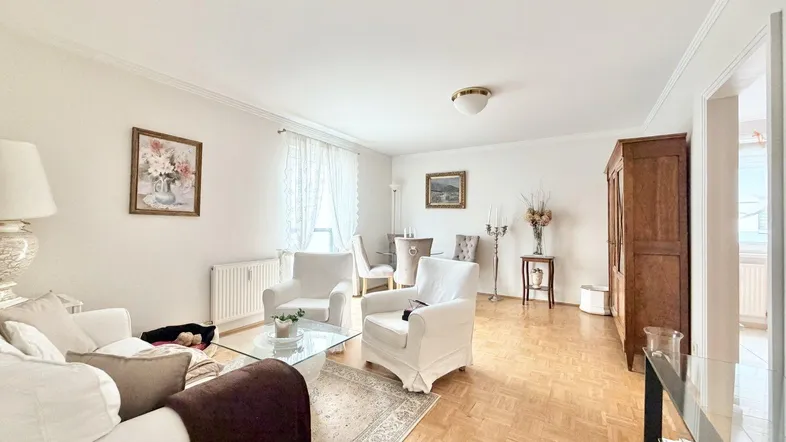 Helles Wohnzimmer mit Parkettboden, bequemen Sesseln und klassischer Einrichtung.