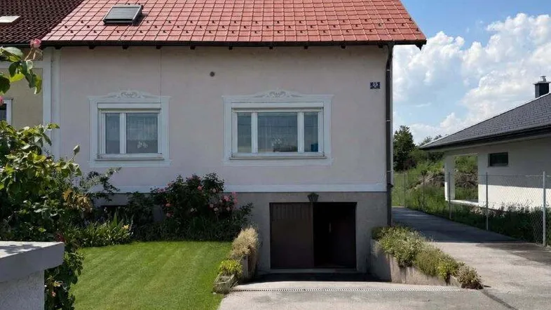 Vorderansicht des Hauses mit gepflegtem Rasen, Einfahrt zur Garage und einem dekorativen Zaun.