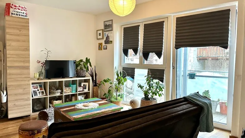 Helles Wohnzimmer mit gemütlichem Sofa, Holzboden und Zugang zu einem Außenbereich.